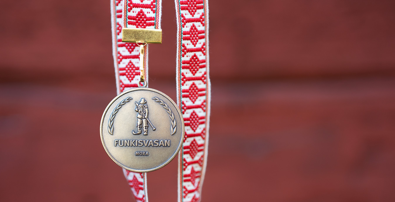 Bild på medaljen för Funkisvasan hängande i ett vävt rödvitt band